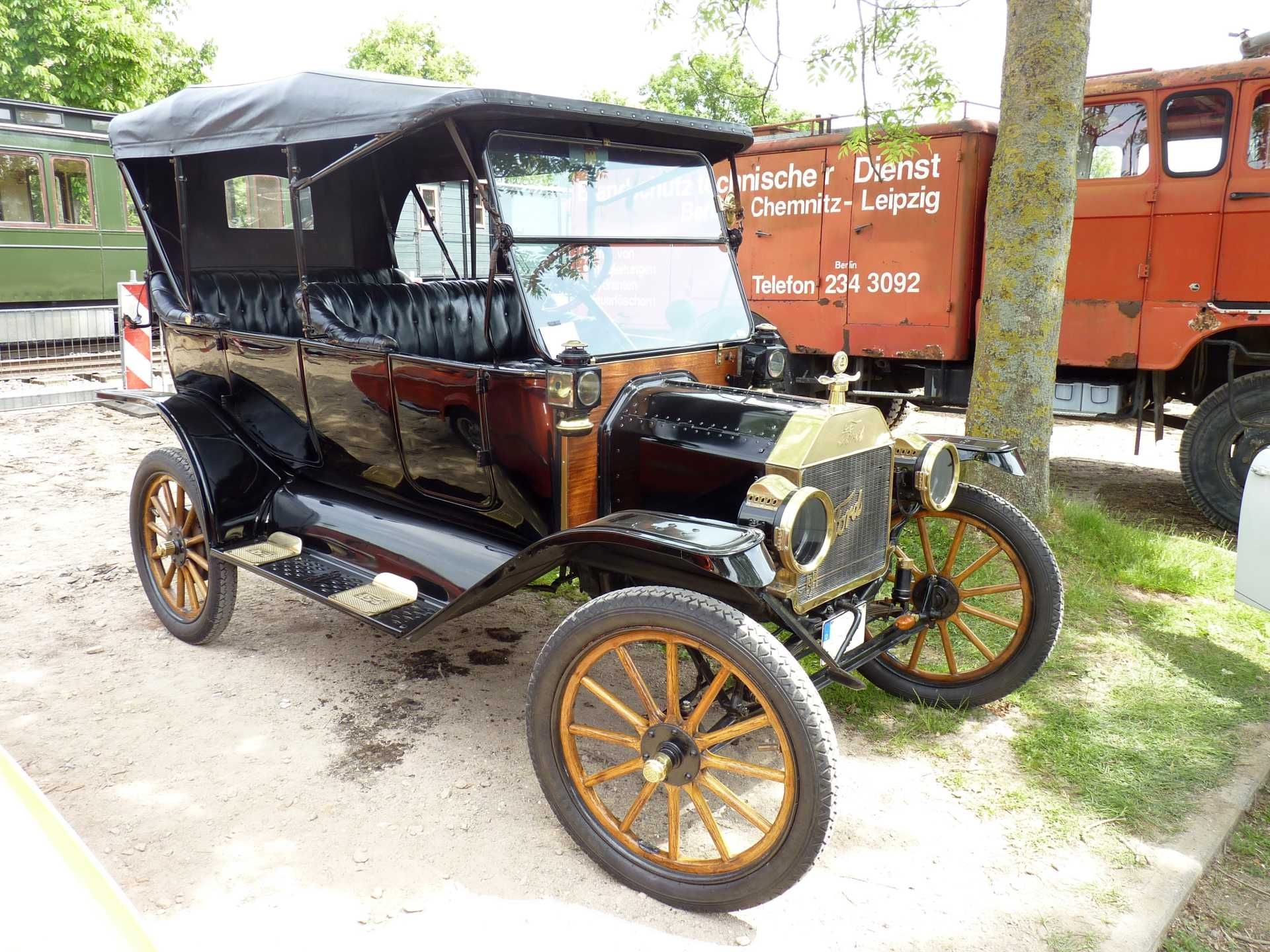Ein altes Auto ist neben einem roten Lastwagen geparkt.