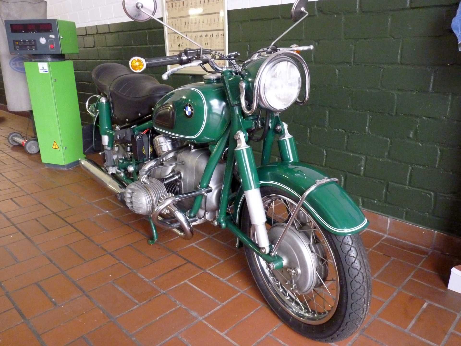 Ein grünes Motorrad ist vor einer grünen Maschine geparkt.