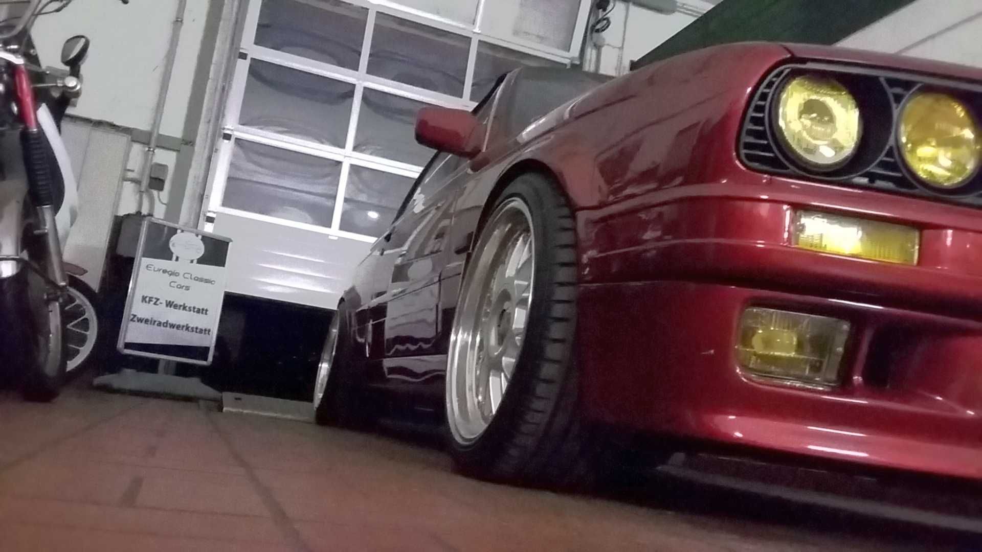 Ein rotes Auto steht in einer Garage neben einem Motorrad