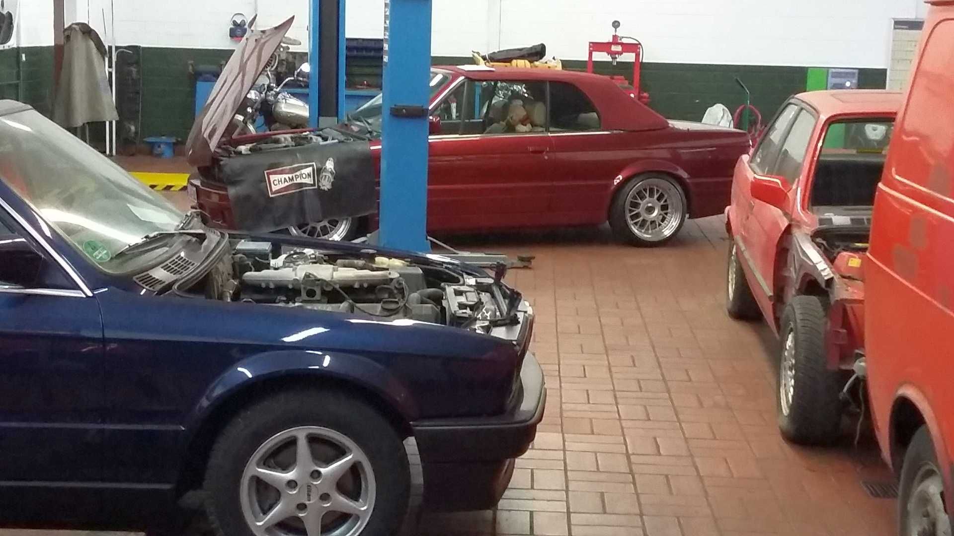 Ein blaues Auto steht neben einem roten Auto in einer Garage