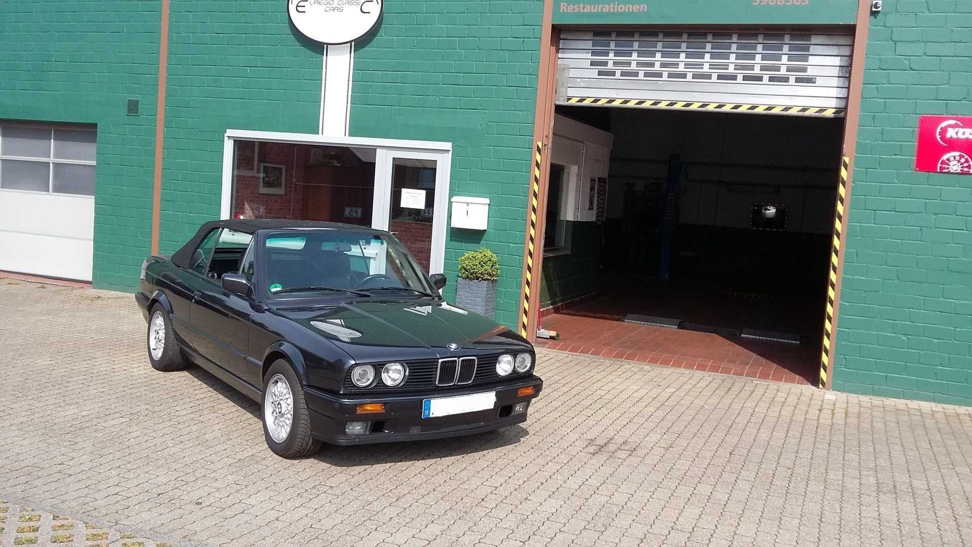 Ein schwarzes Auto steht vor einem grünen Gebäude