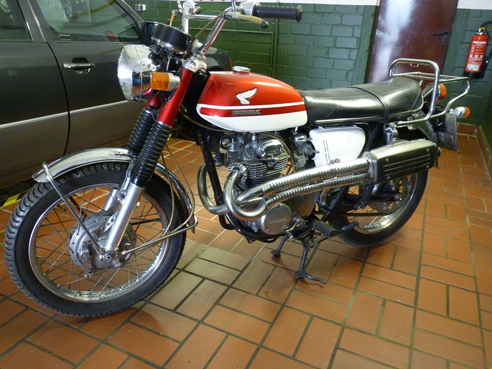 Ein rot-weißes Honda-Motorrad steht auf einem gefliesten Boden