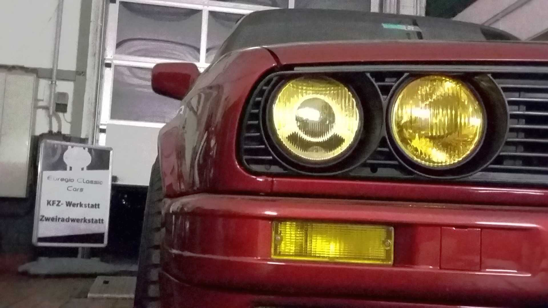 Ein rotes Auto mit gelben Scheinwerfern steht in einer Garage.