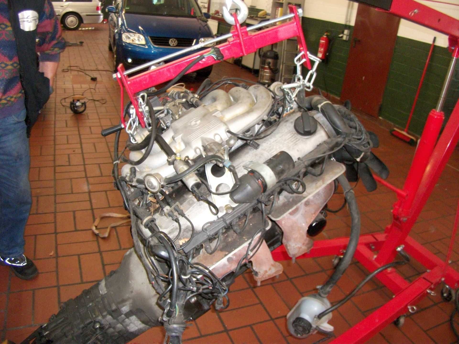 Ein Automotor wird von einem roten Kran angehoben