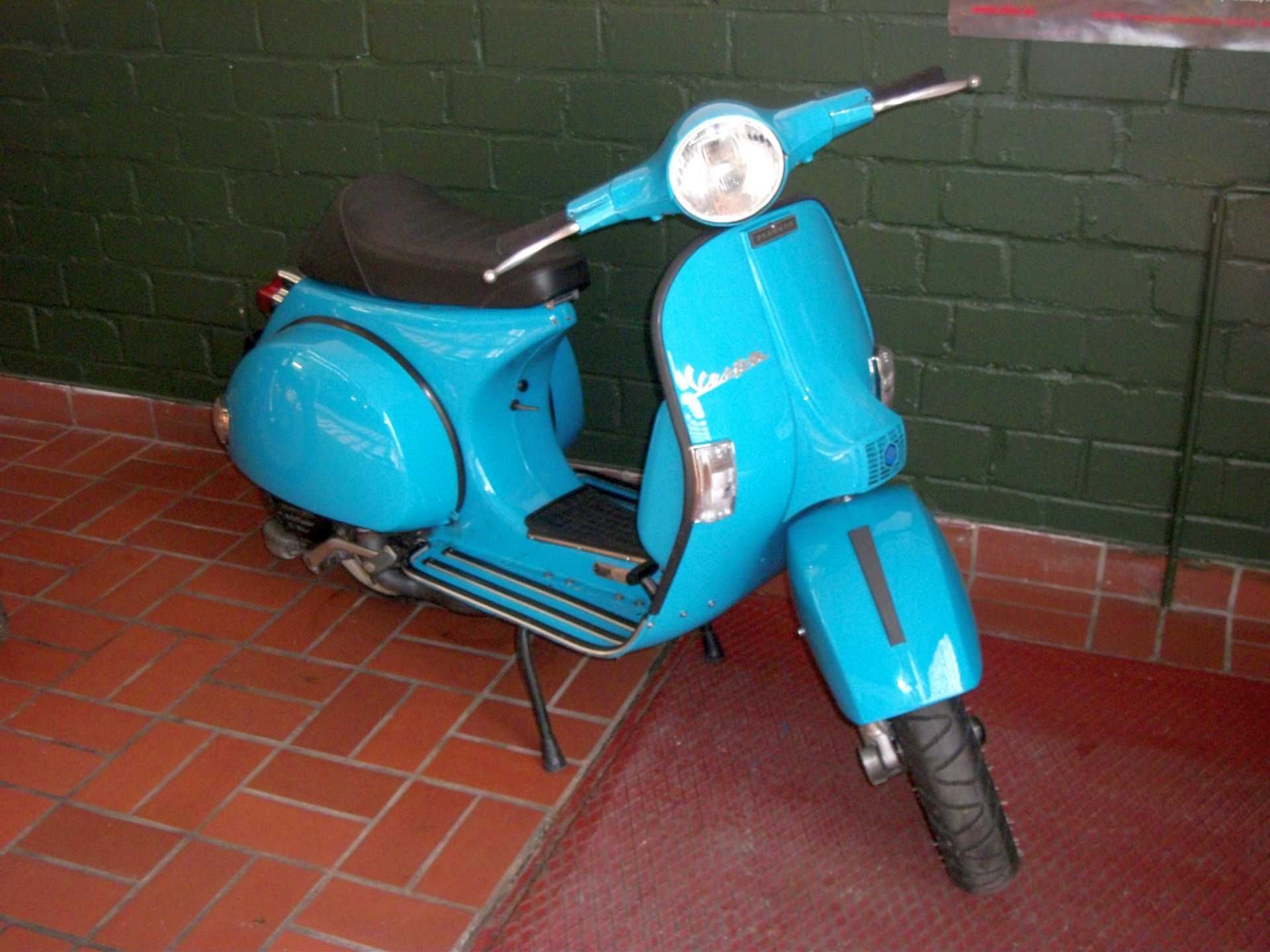 Ein blauer Roller steht vor einer Backsteinmauer