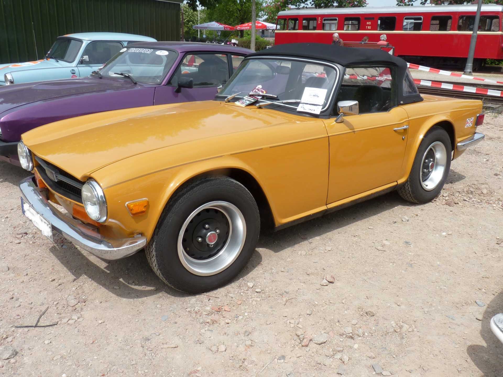 Ein gelber Sportwagen steht neben einem violetten Auto