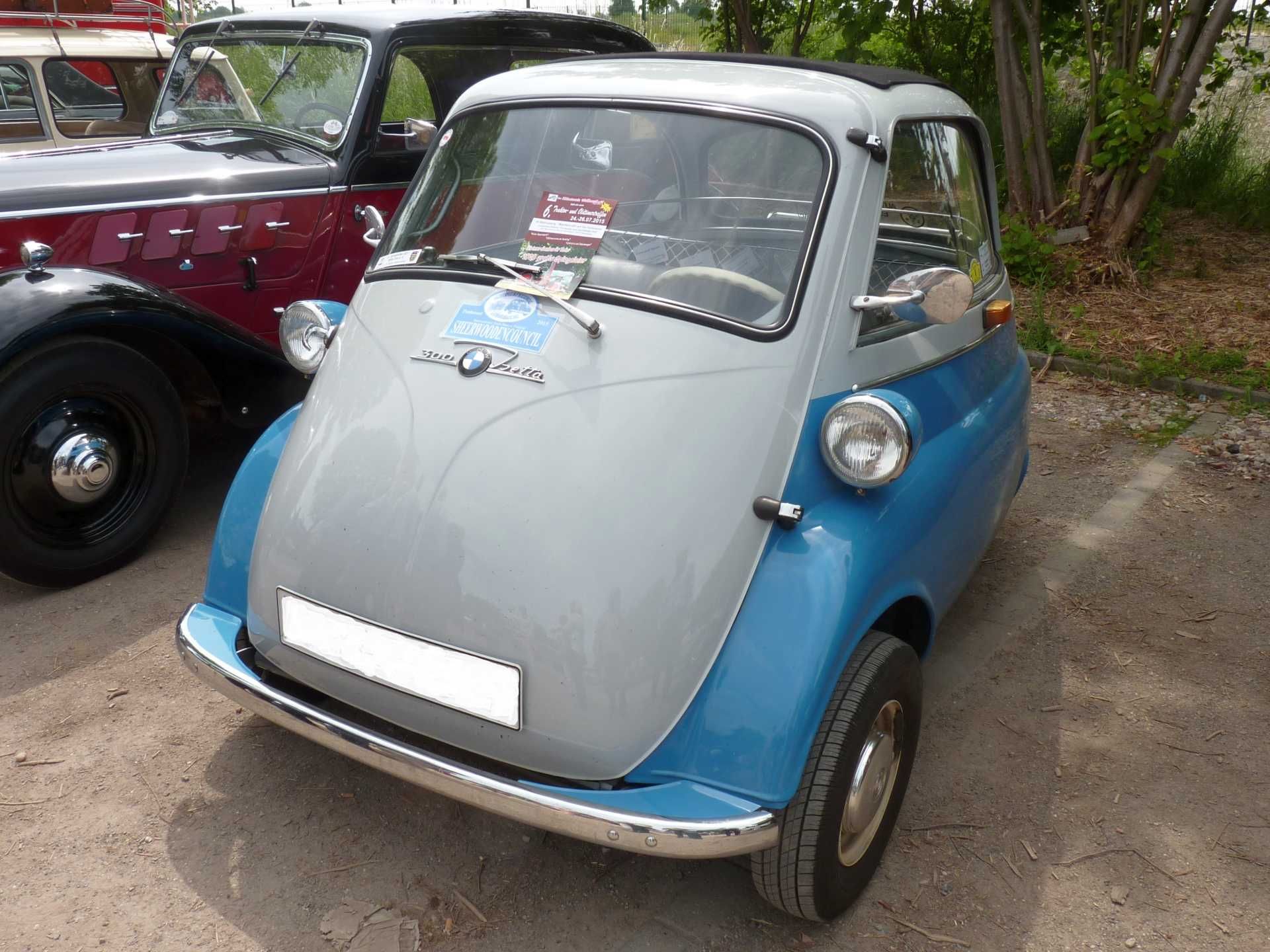 Ein kleines blau-graues Auto steht neben einem roten Auto