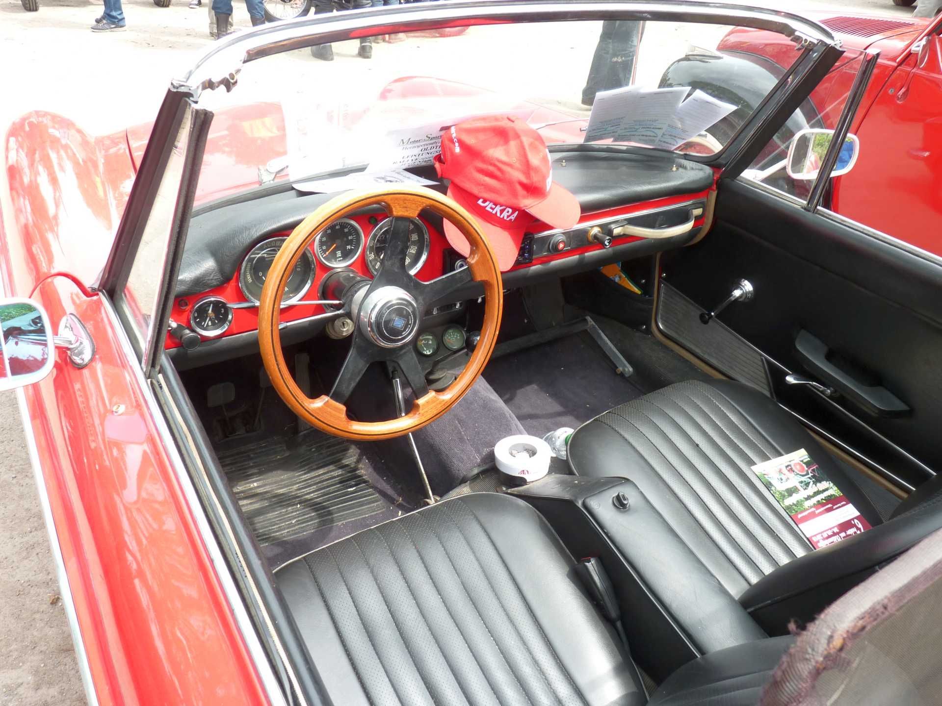 Ein rotes Auto mit schwarzen Sitzen und einem Holzlenkrad