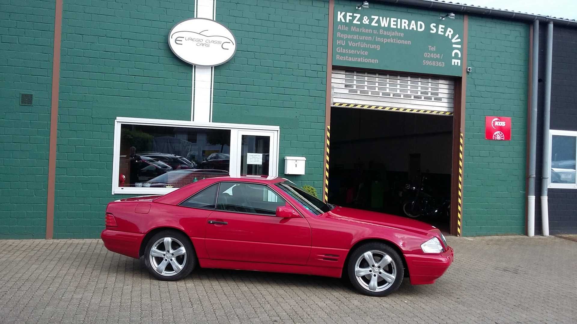 Ein rotes Auto steht vor einem grünen Gebäude