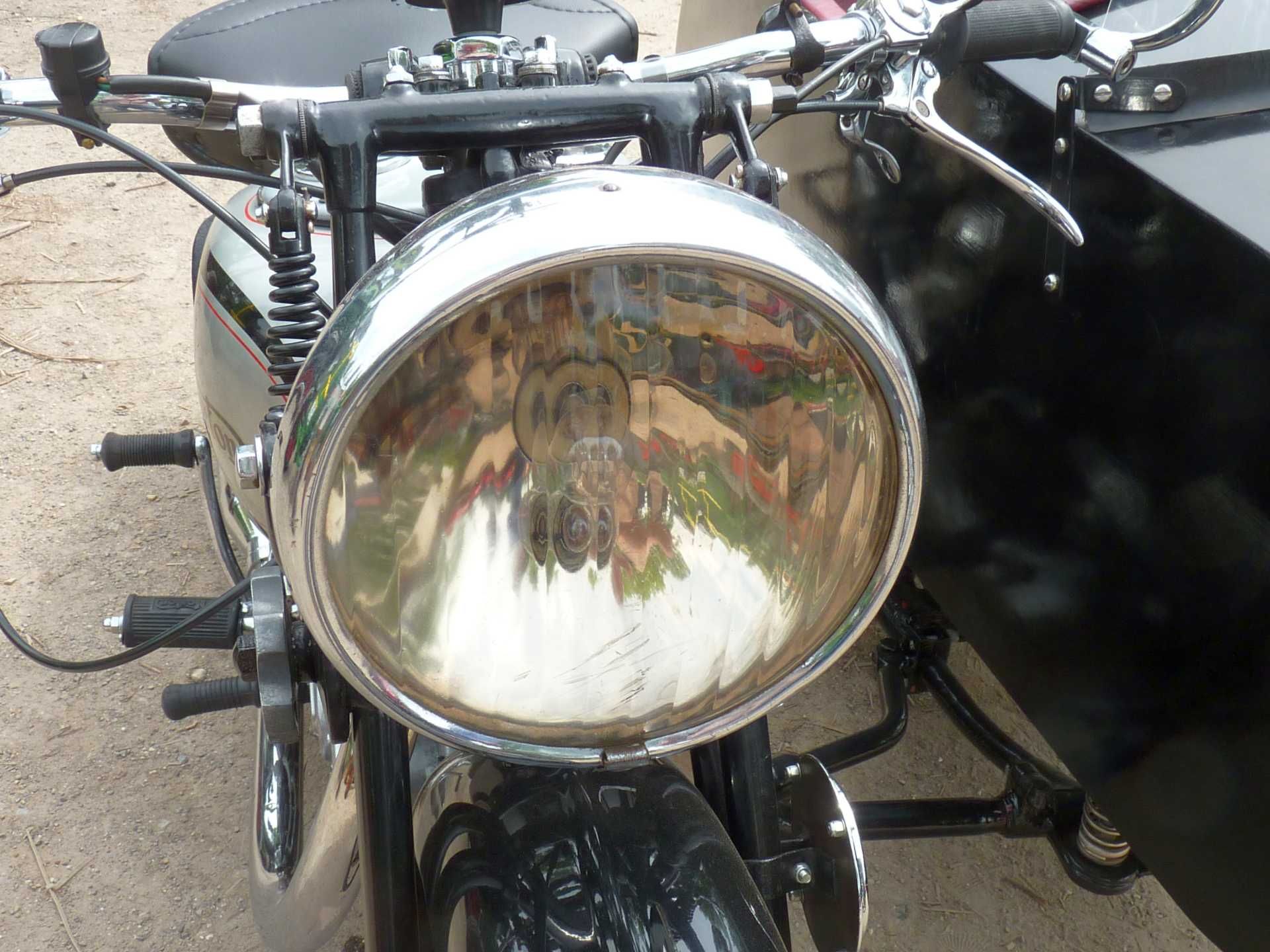 Eine Nahaufnahme von einem Motorradscheinwerfer mit einem Beiwagen im Hintergrund