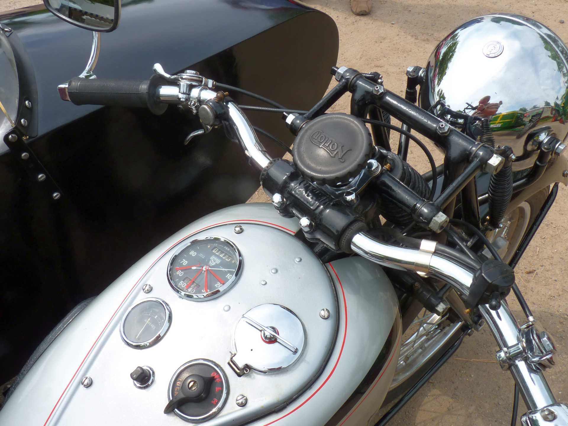 Ein silbernes Motorrad mit schwarzem Beiwagen steht auf einem Feldweg