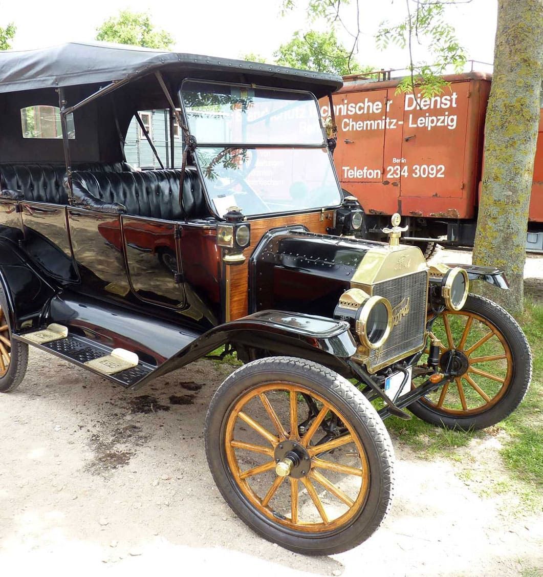 Ein altes Auto steht neben einem roten LKW mit der Aufschrift „Chemie Everist“
