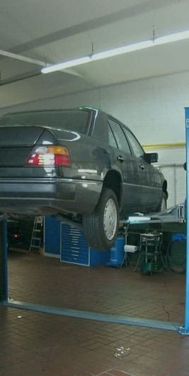 Ein Auto steht auf einer Hebebühne in einer Garage.