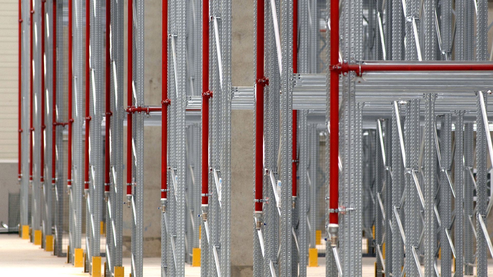 Una fila de estantes de metal en un almacén con postes rojos.