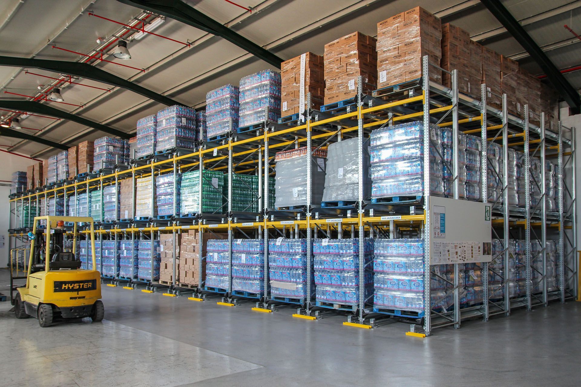 Una carretilla elevadora amarilla circula por un gran almacén.