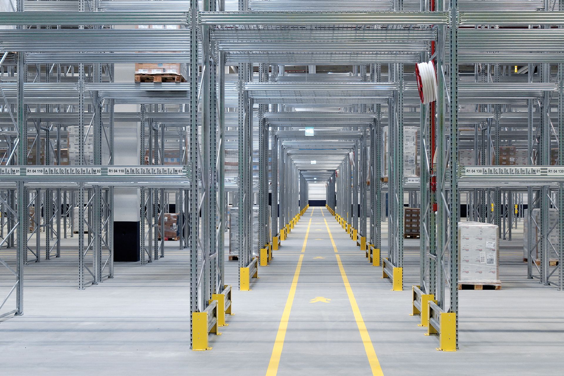 Un almacén vacío con muchos estantes y una línea amarilla en el suelo.