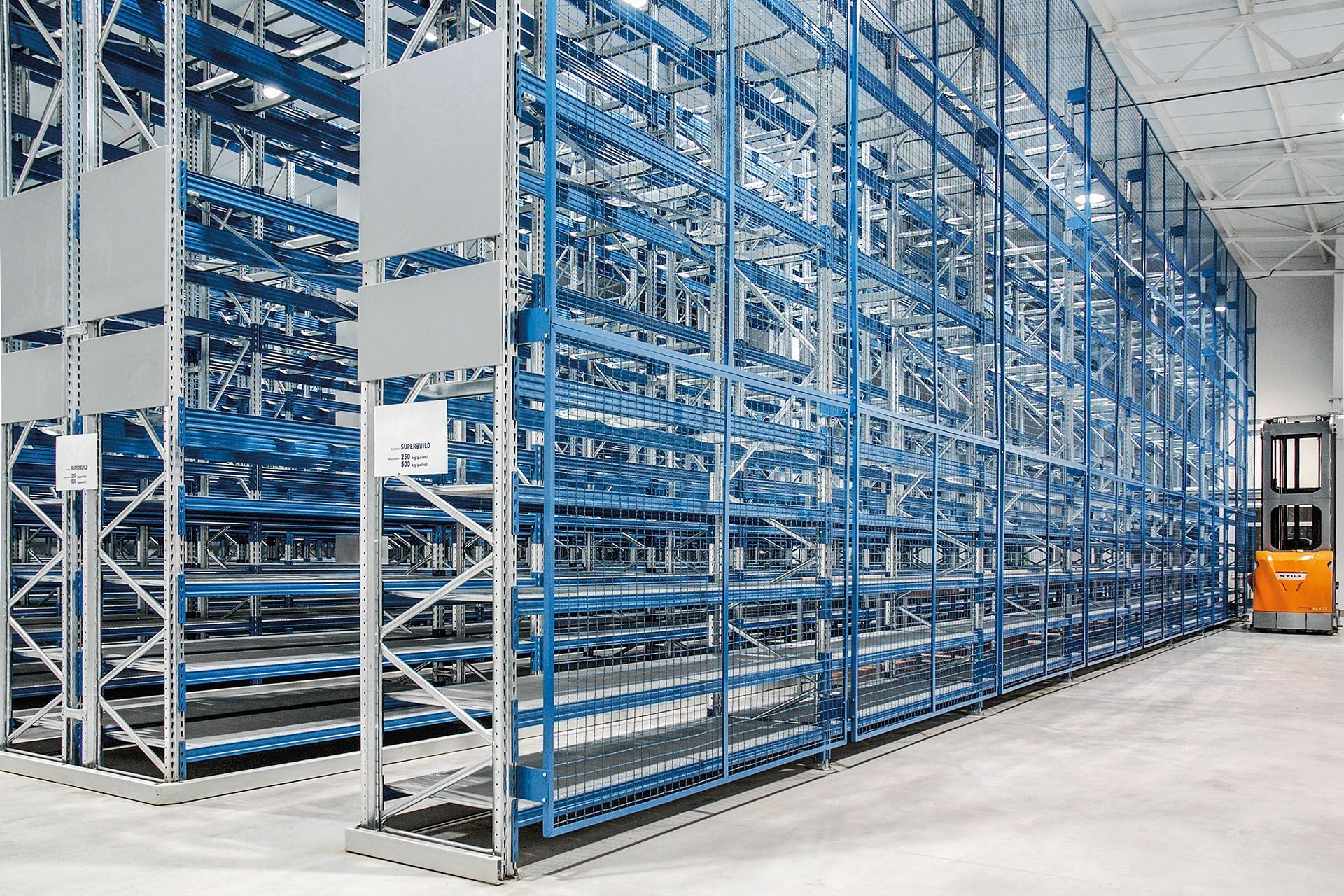 Una carretilla elevadora circula por un gran almacén lleno de estanterías.