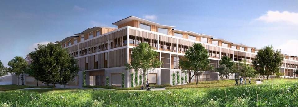 Modernes mehrstöckiges Gebäude mit heller Fassade, Holzelementen und Balkonen, eingebettet in eine grüne Landschaft mit Bäumen.