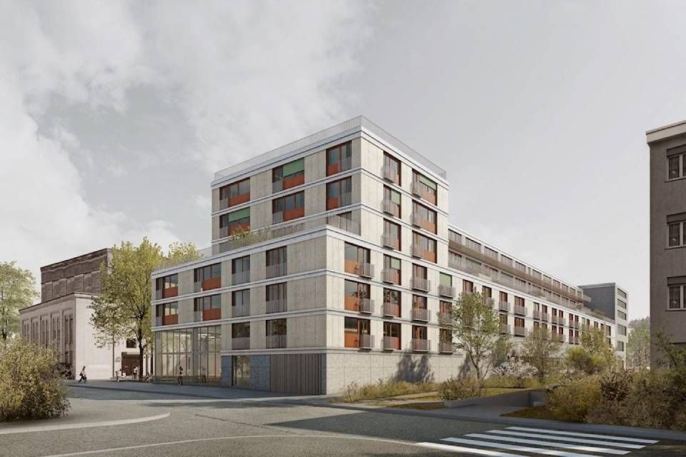 Modernes Mehrfamilienhaus mit grauer Fassade, braunen Balkonen und Dachterrasse an einer Strassenecke.