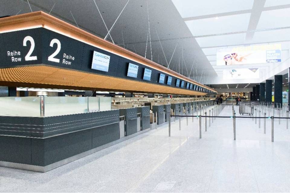 Leere Check-in-Schalter am Flughafen mit digitalen Bildschirmen; ein Schild weist auf Gate 22 hin.