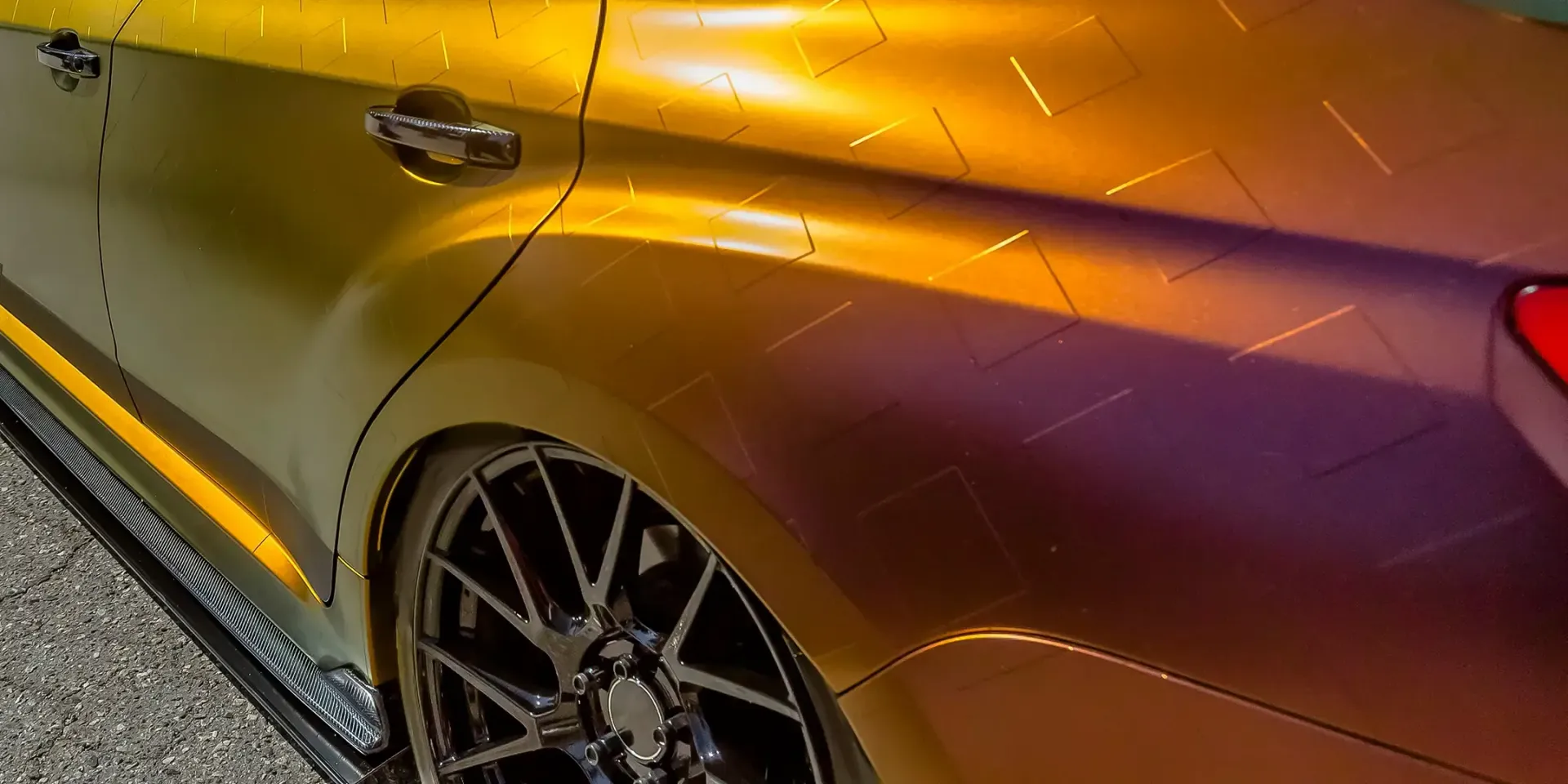 Eine Nahaufnahme der Seite eines Autos mit einer farbwechselnden Lackierung in Gelb- und Violetttönen.