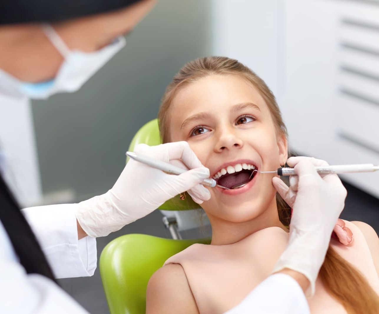 Una niña se está haciendo examinar los dientes por un dentista