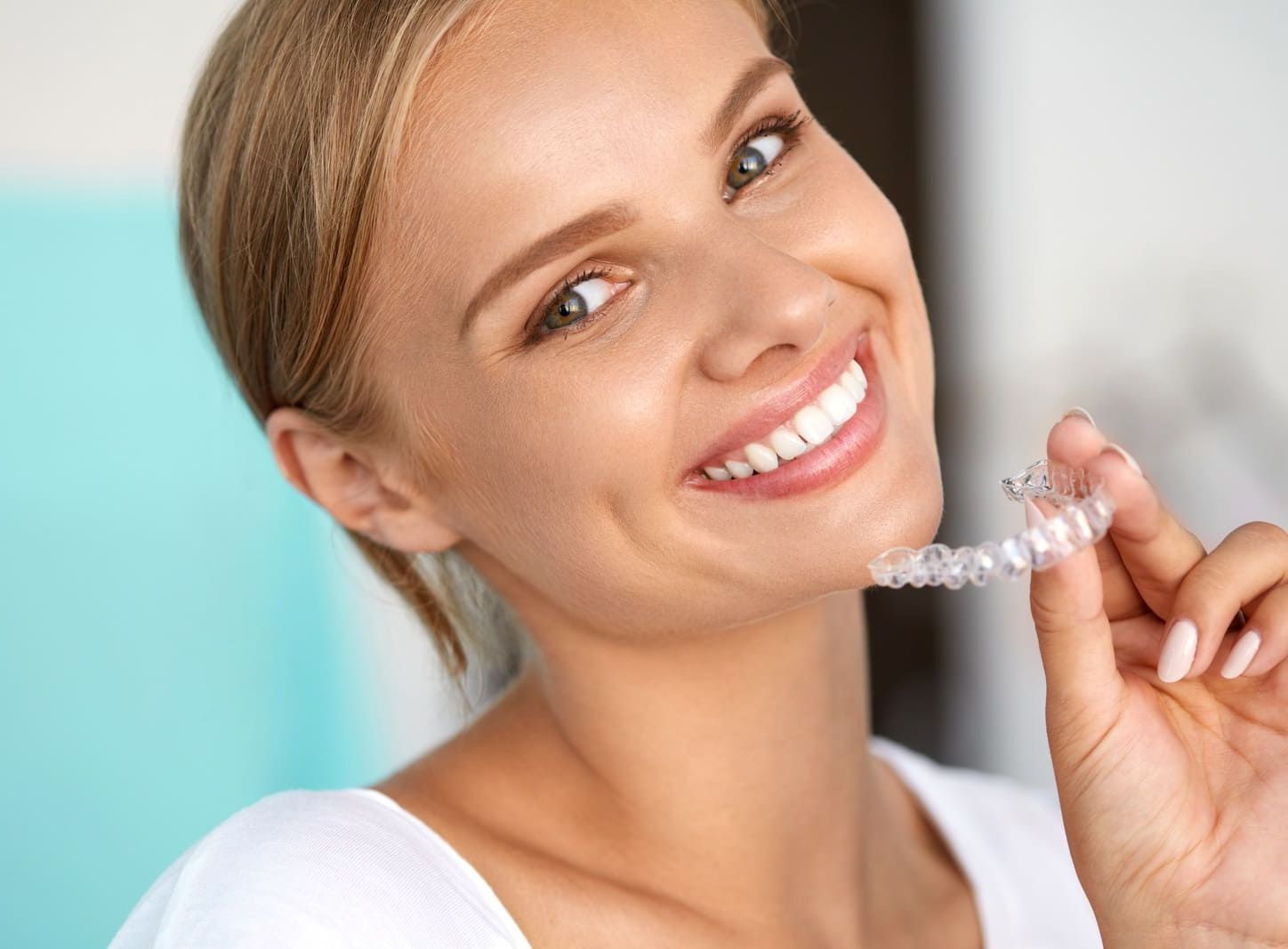 Una mujer sonríe mientras sostiene un retenedor transparente en su mano.