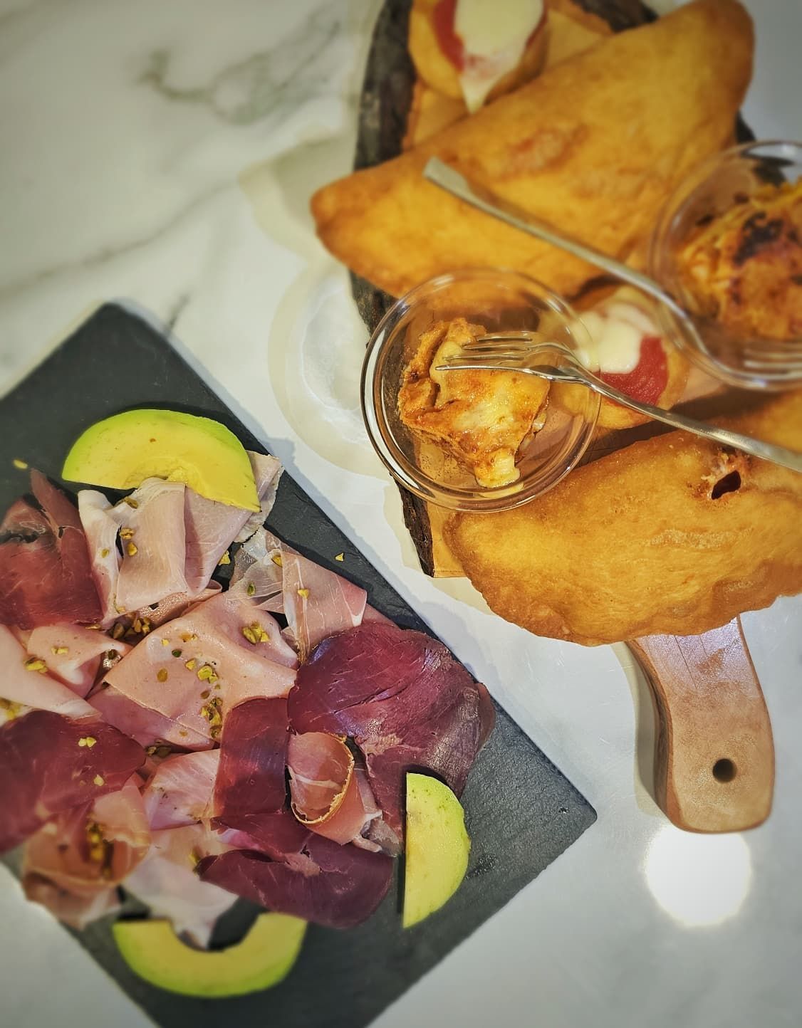 Interno di un bar con bancone, tavoli, sedie e una porta.