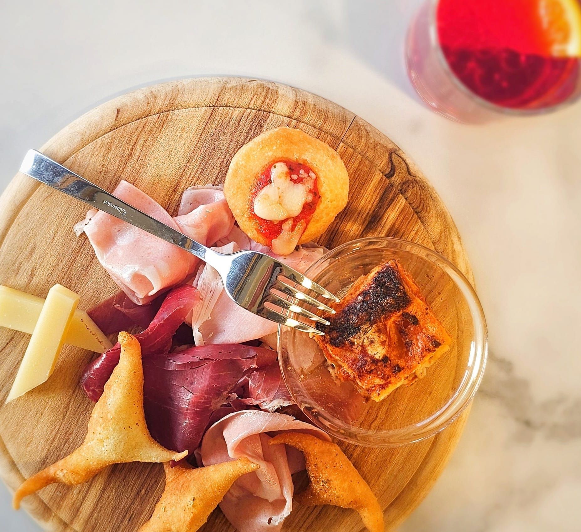 Calamari fritti con salsa, guarnito con carota e rametto di erbe aromatiche su un piatto bianco.