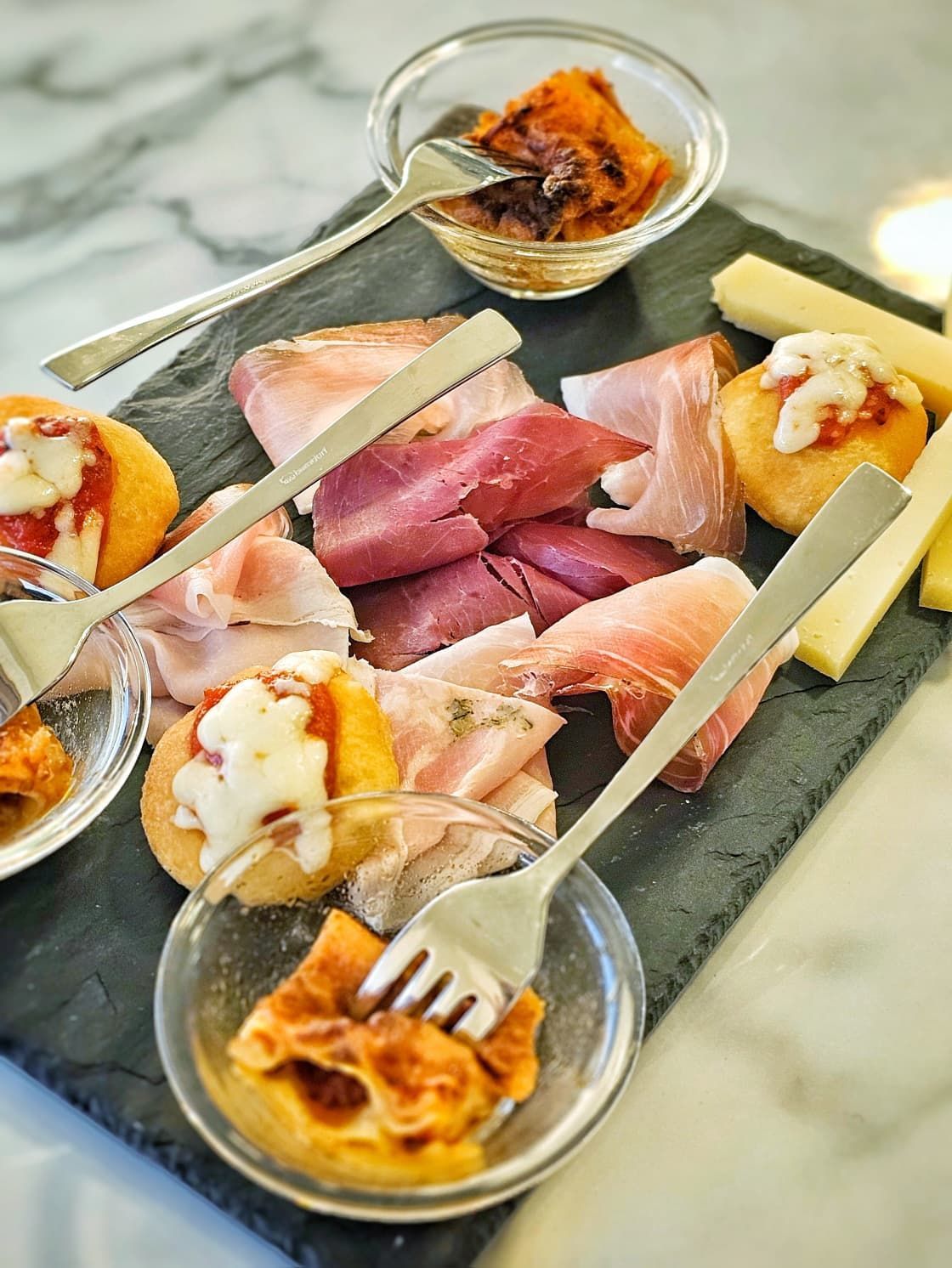 Due taglieri con antipasti: formaggi e salumi su una superficie di marmo.