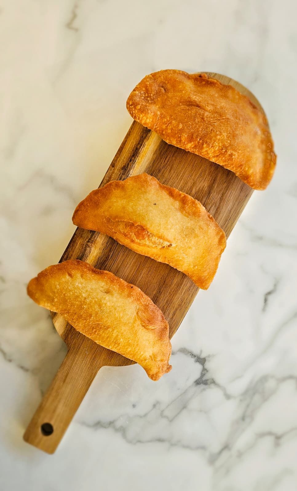 Due empanadas dorate con salsa, servite su una lavagna nera.