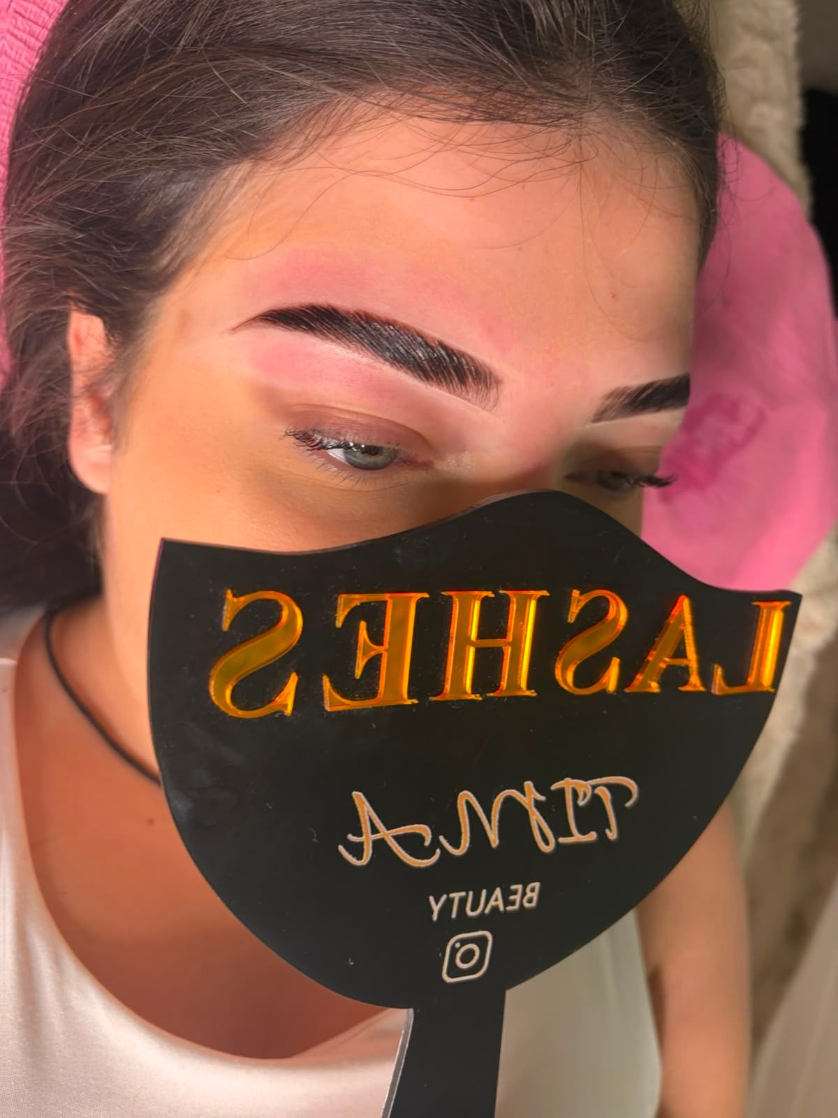 Femme portant un masque noir à inscription dorée, se reposant les yeux fermés à l'intérieur.