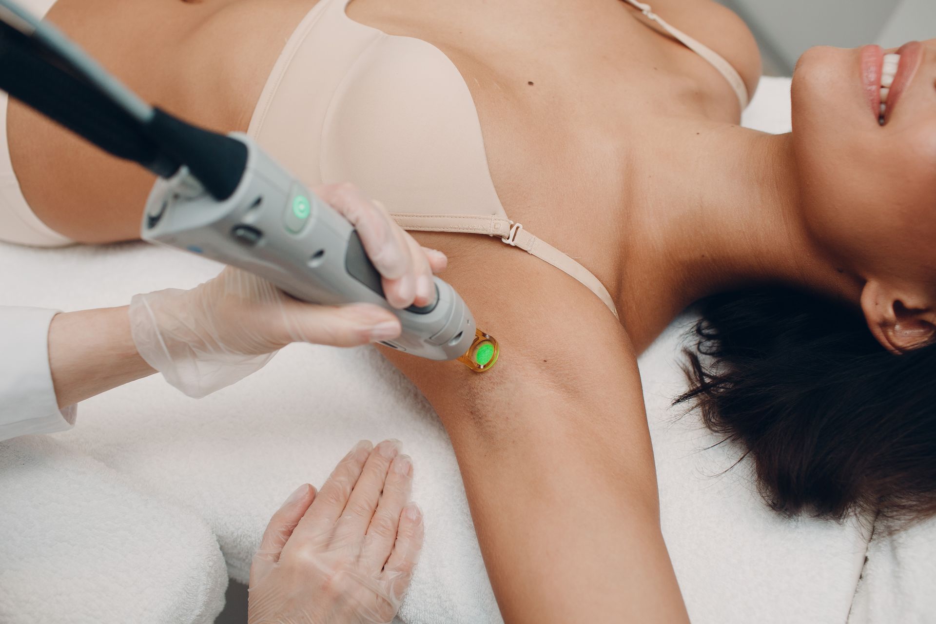 Traitement esthétique des aisselles d'une femme à l'aide d'un appareil laser portatif et de mains gantées.