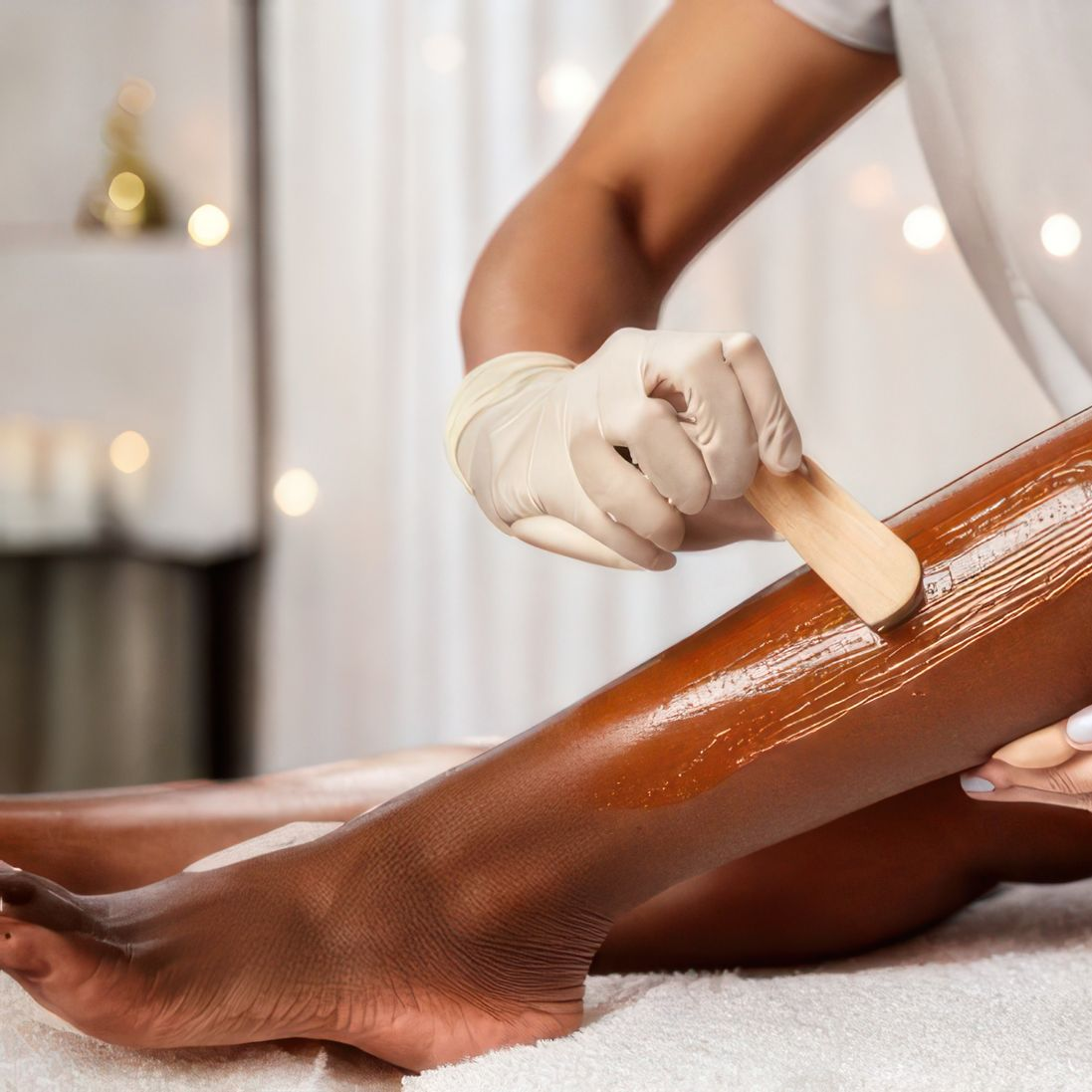 Main gantée épilant la jambe d'une cliente dans une cabine de soin spa.