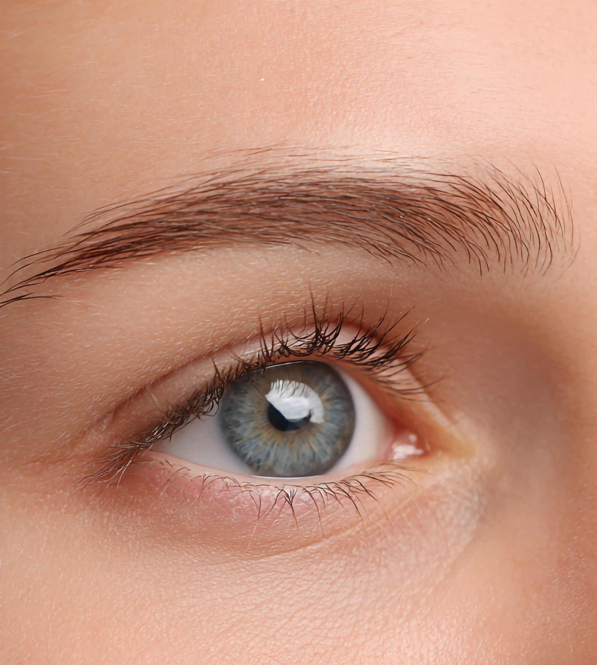 Gros plan sur un œil et un sourcil bleus sur une peau lisse.