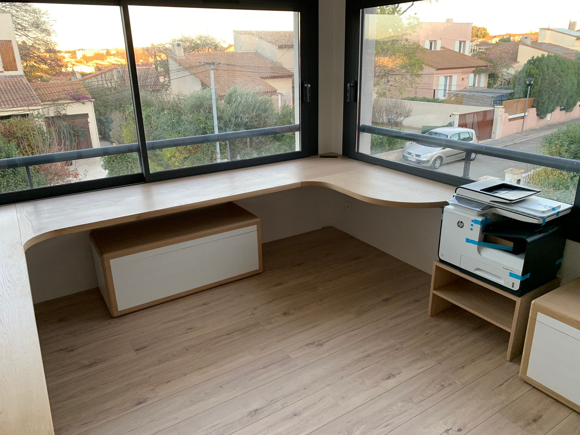 Une pièce avec un bureau et une fenêtre avec vue sur une ville.