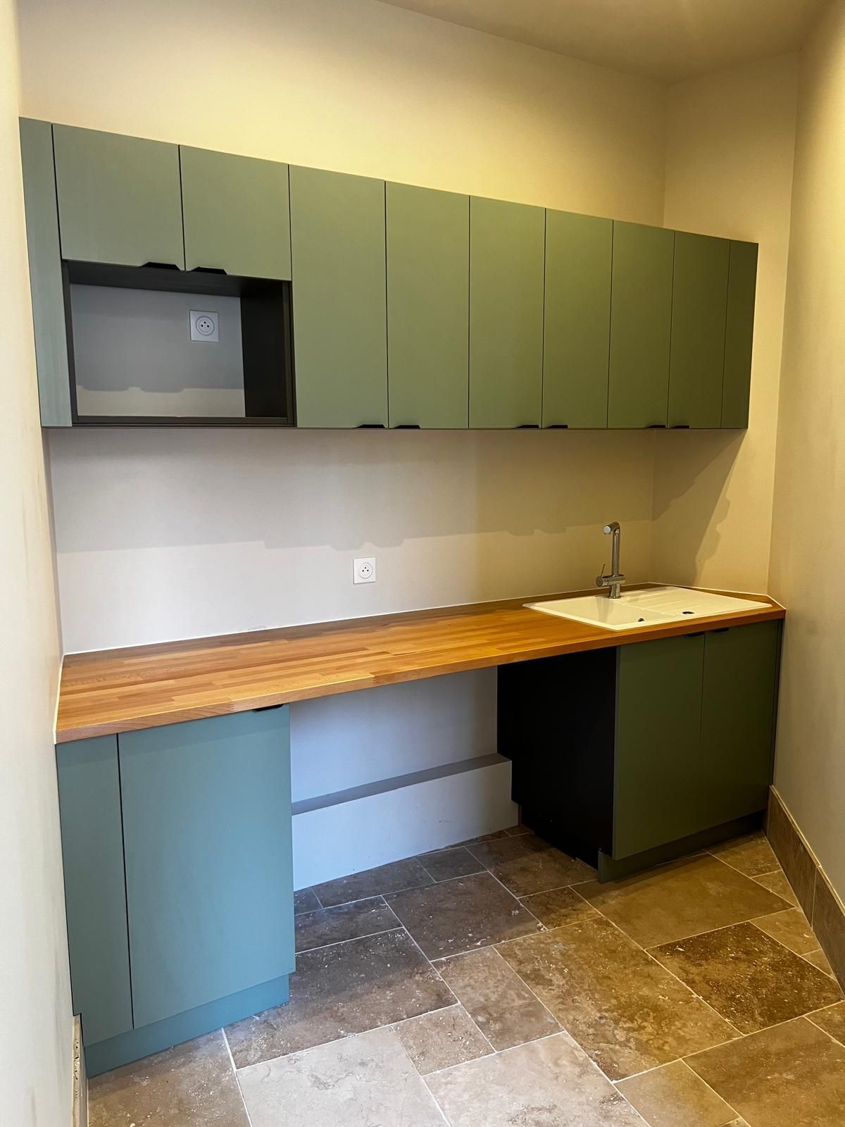 Une cuisine avec des armoires vertes et un comptoir en bois.