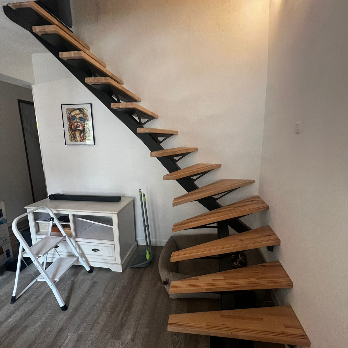 Un escalier en bois dans un salon à côté d'une échelle