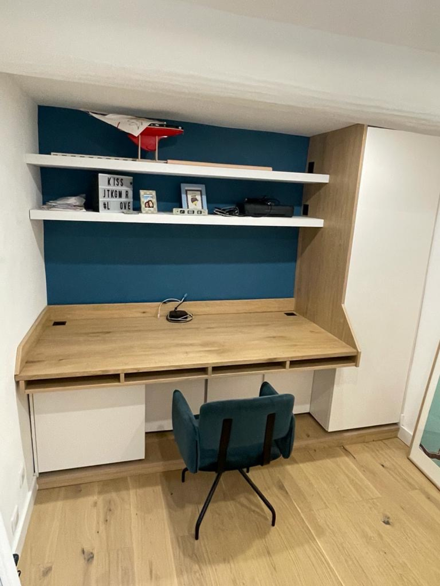 Un bureau en bois avec une chaise dans une pièce avec un mur bleu.