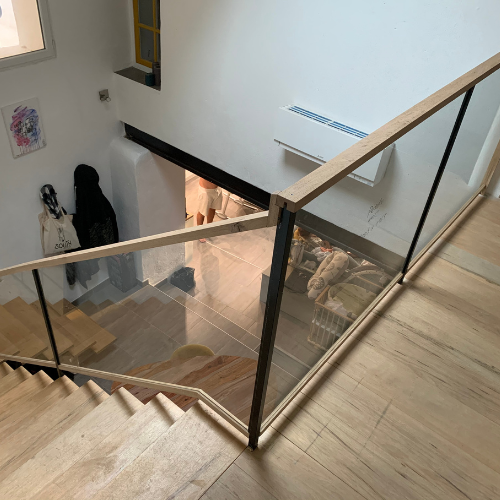 Un escalier en bois avec une rampe en verre dans une maison.