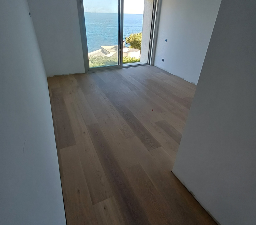 Une chambre avec un plancher en bois et une grande fenêtre donnant sur l'océan.