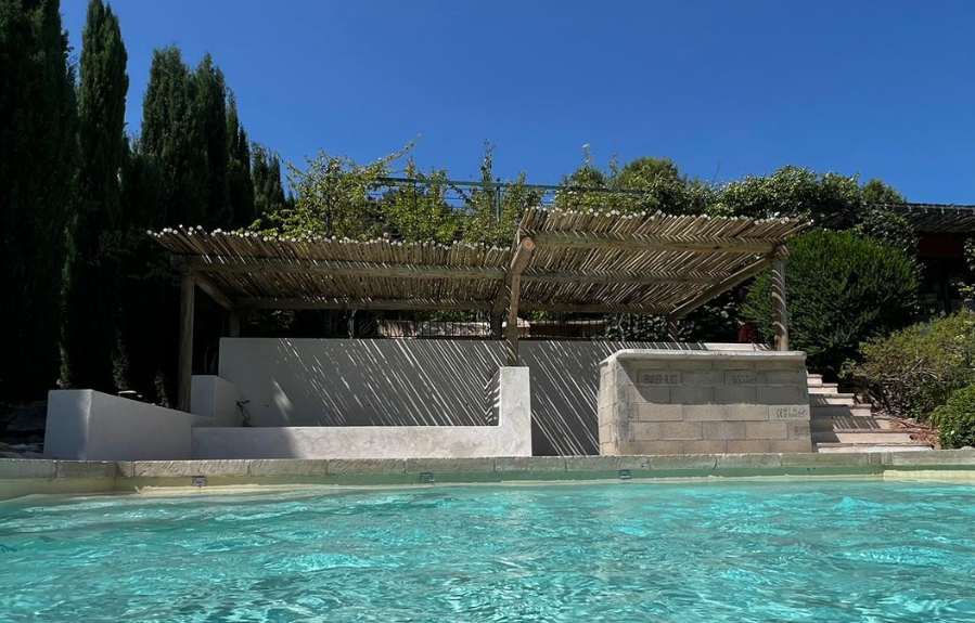 Pergola couvrant le bar et le transat XXL en maçonnerie devant une piscine