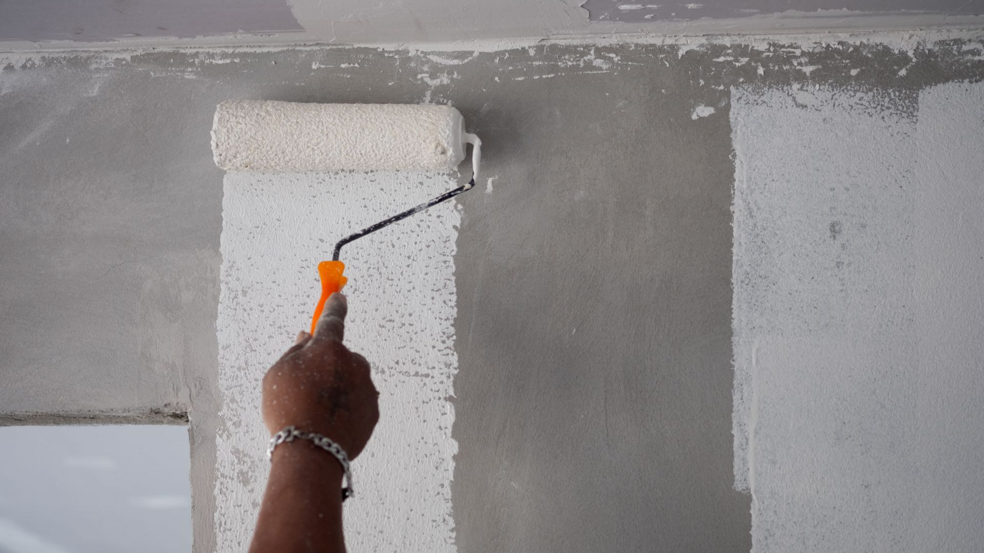 Un peintre applique de la peinture sur une façade intérieure