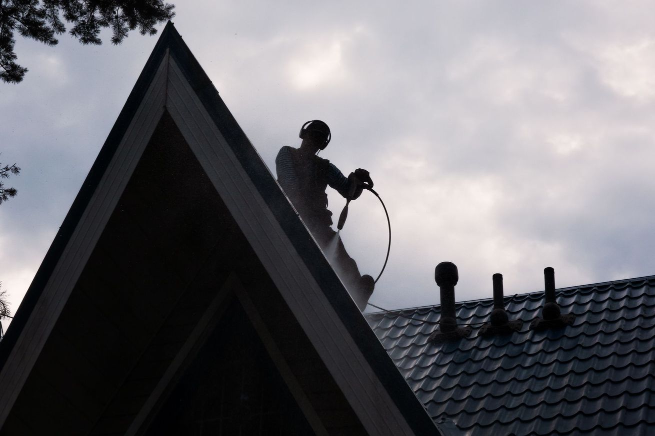 Un professionnel lave des tuiles sur un toit en pente