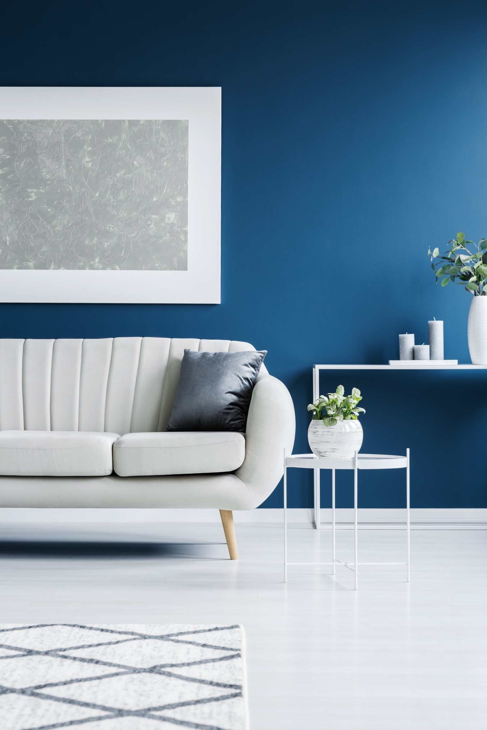 Una sala de estar con paredes azules y un sofá blanco.