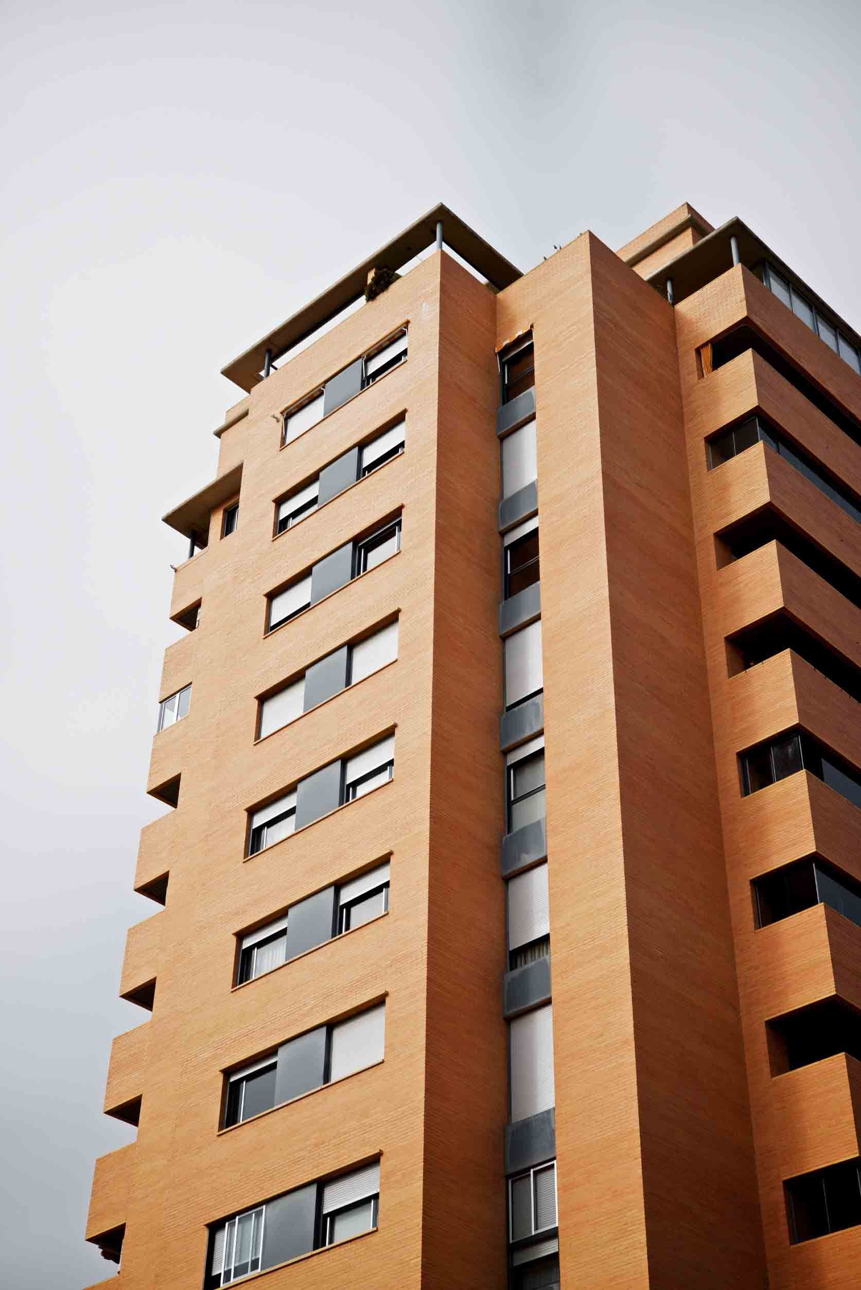 Mirando hacia arriba a un edificio alto de ladrillo con muchas ventanas