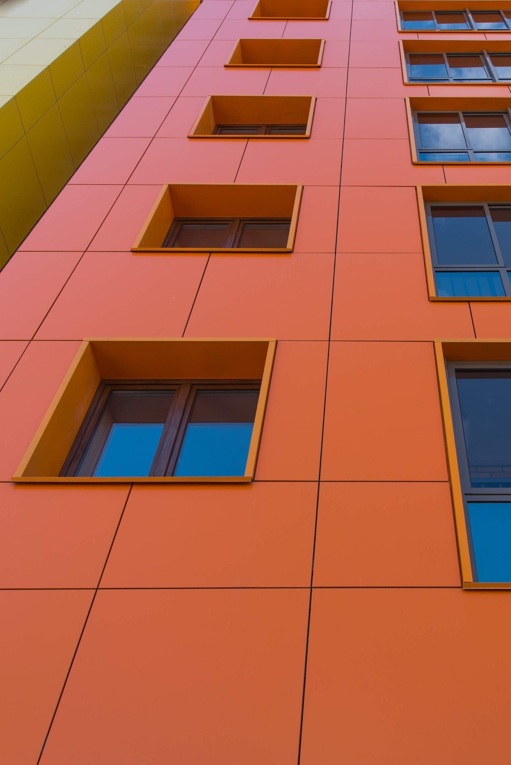 Un primer plano de un edificio naranja con ventanas azules.