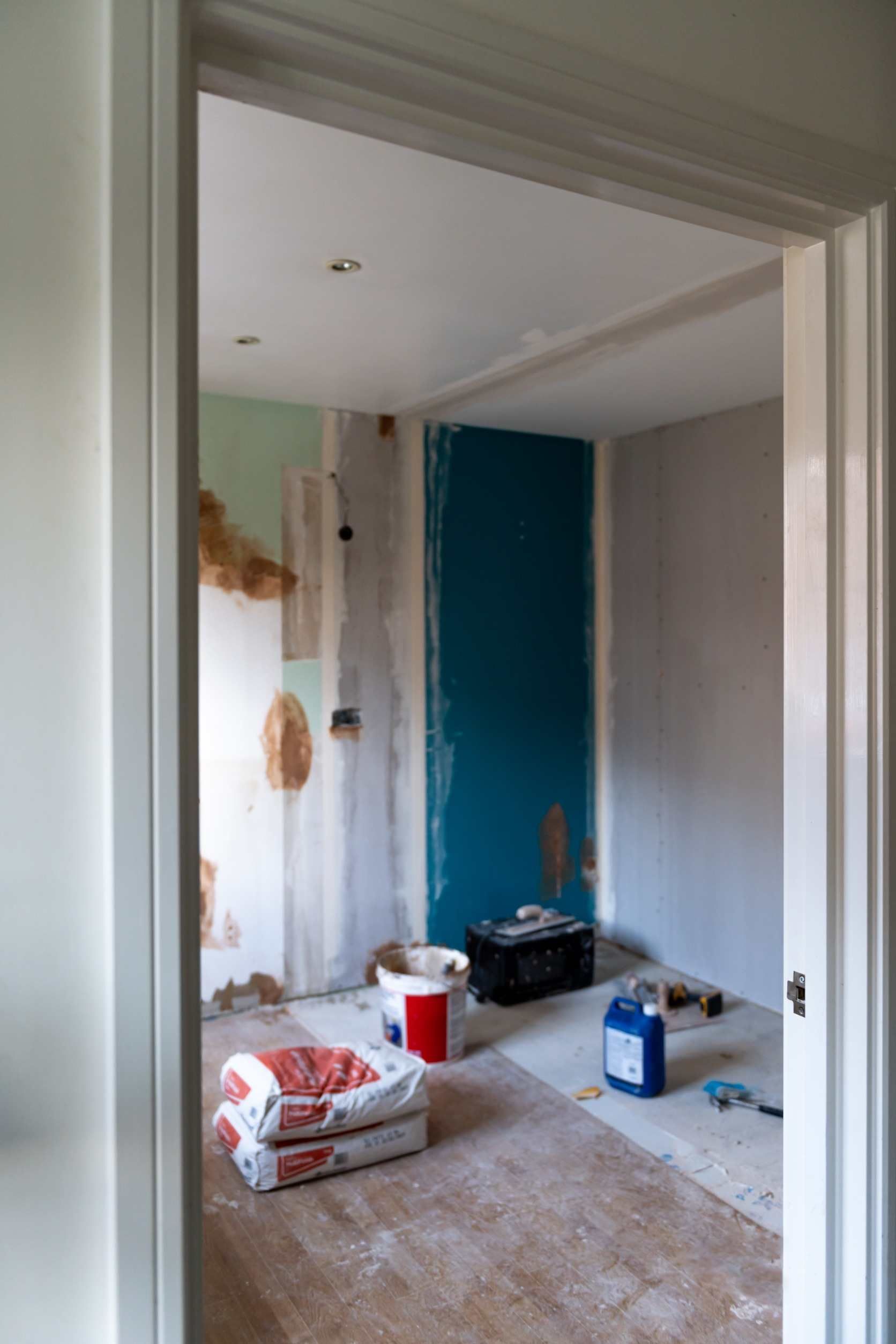 Una habitación con una puerta azul y una bolsa de cemento en el suelo.