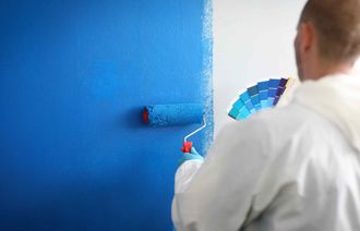 Un hombre está pintando una pared azul con un rodillo de pintura.