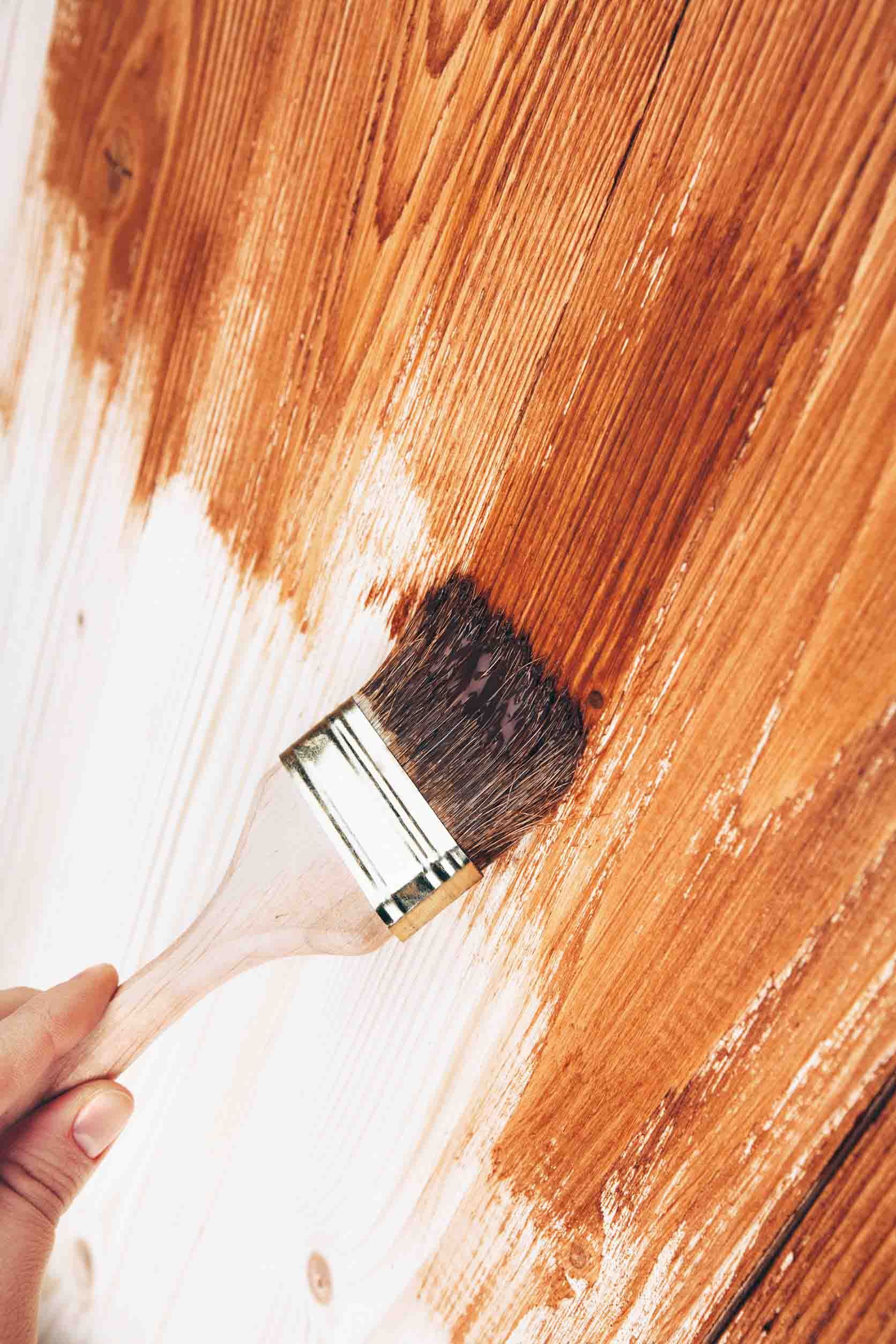Una persona está pintando una superficie de madera con un pincel.